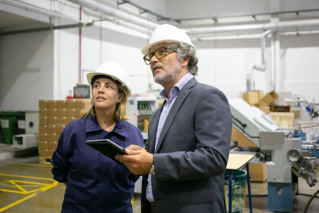 A supervisor and an operator using a tablet to check production controls in a factory